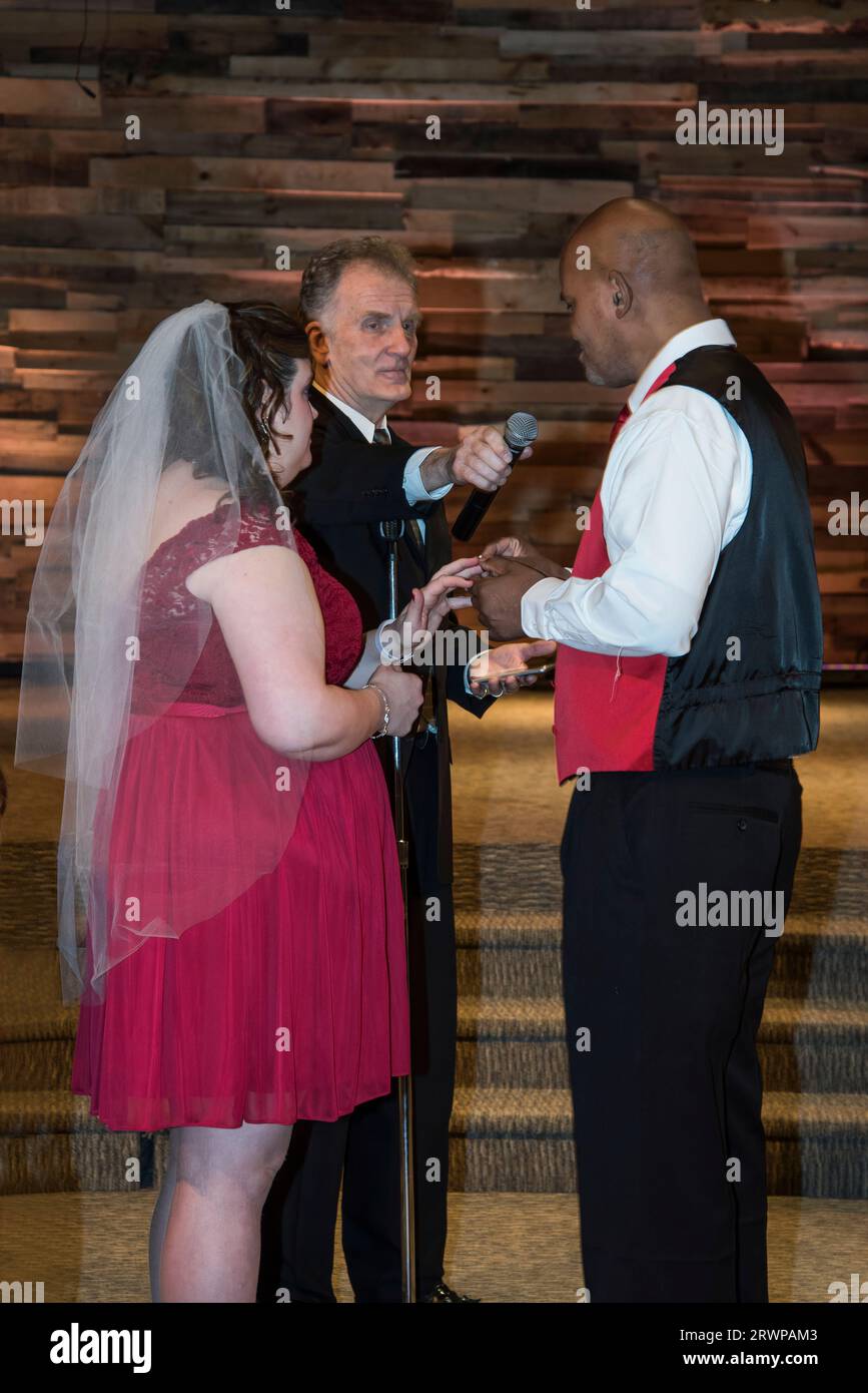 Maplewood, Minnesota. Couple interracial disant leurs vœux de mariage avec le marié mettant la bague sur la mariée lors d'une cérémonie chrétienne. Banque D'Images Maplewood, Minnesota. Couple interracial disant leurs vœux de mariage avec le marié mettant la bague sur la mariée lors d'une cérémonie chrétienne. Banque D'Images