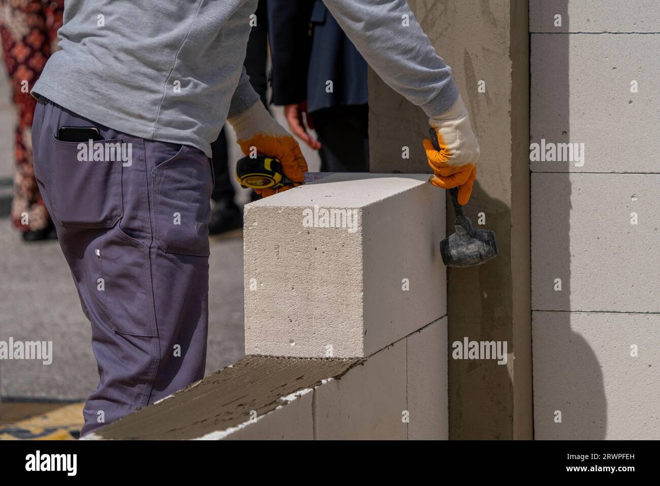 Le maçon fonctionne. Construction d'un mur en béton cellulaire. Banque D'Images