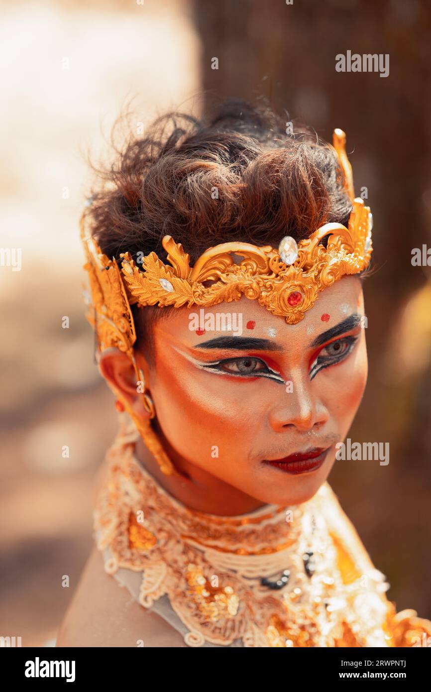 Gros plan sur le visage d'un homme asiatique maquillé avec une couronne d'or sur la tête et un collier d'or sur son corps en visitant le village Banque D'Images