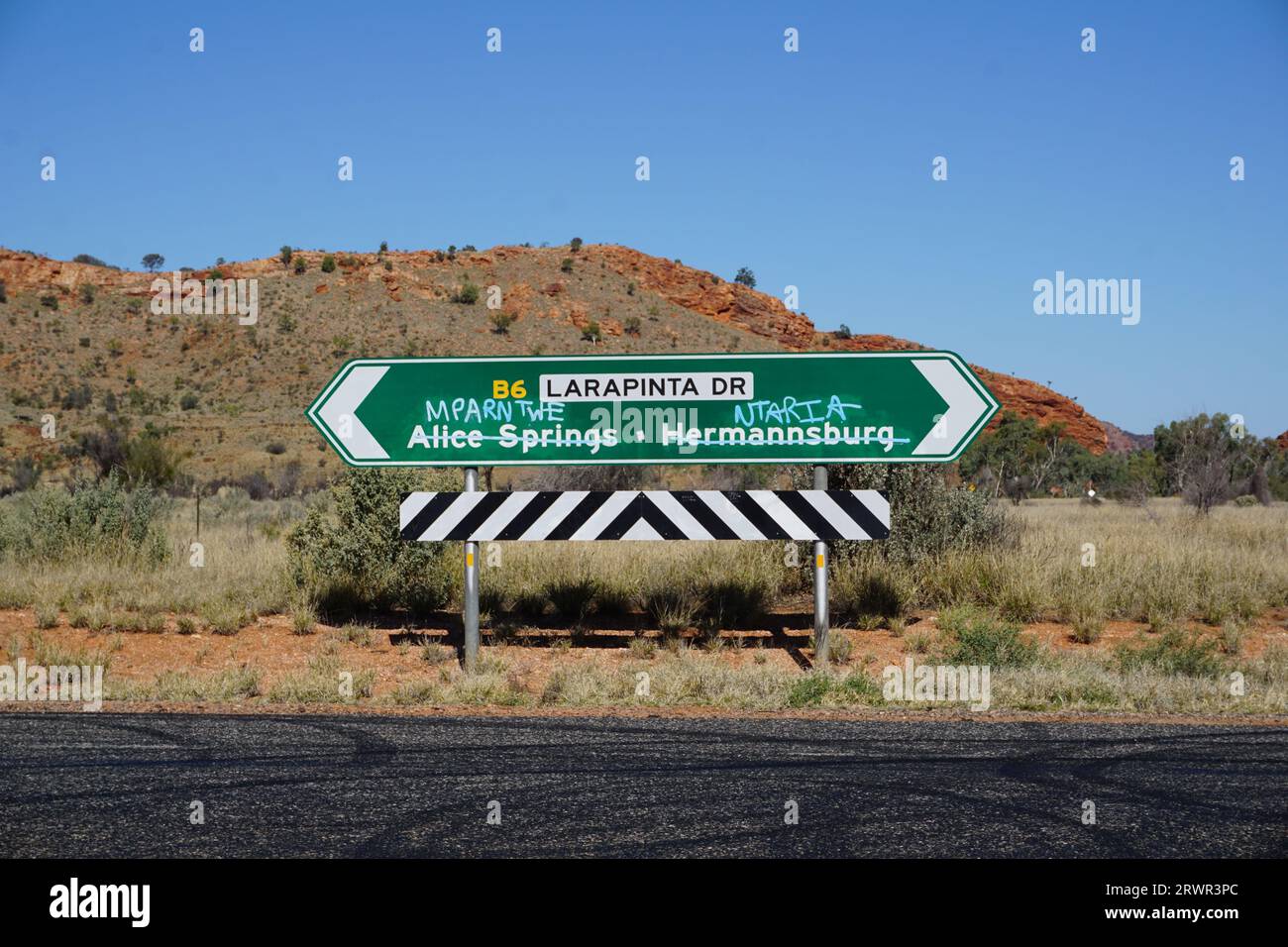 Panneau routier avec noms anglais barré et remplacé par des noms aborigènes avec graffiti près d'Alice Springs, territoire du Nord, Australie Banque D'Images