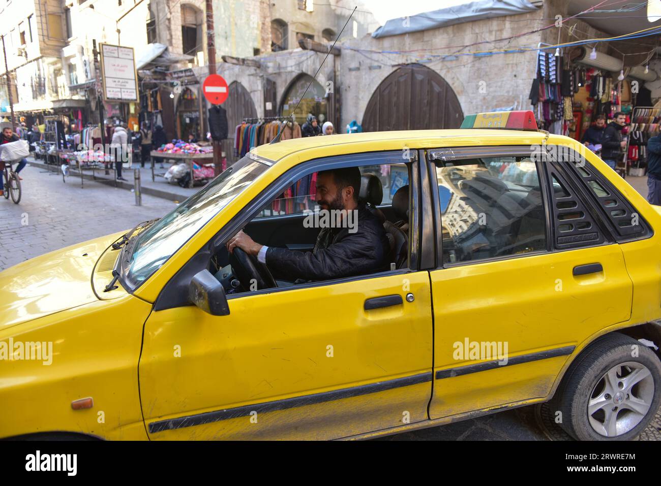 Un sympathique chauffeur de taxi a ralenti son taxi jaune pour être photographié avec un grand sourire sur le visage, à Hama, en Syrie Banque D'Images