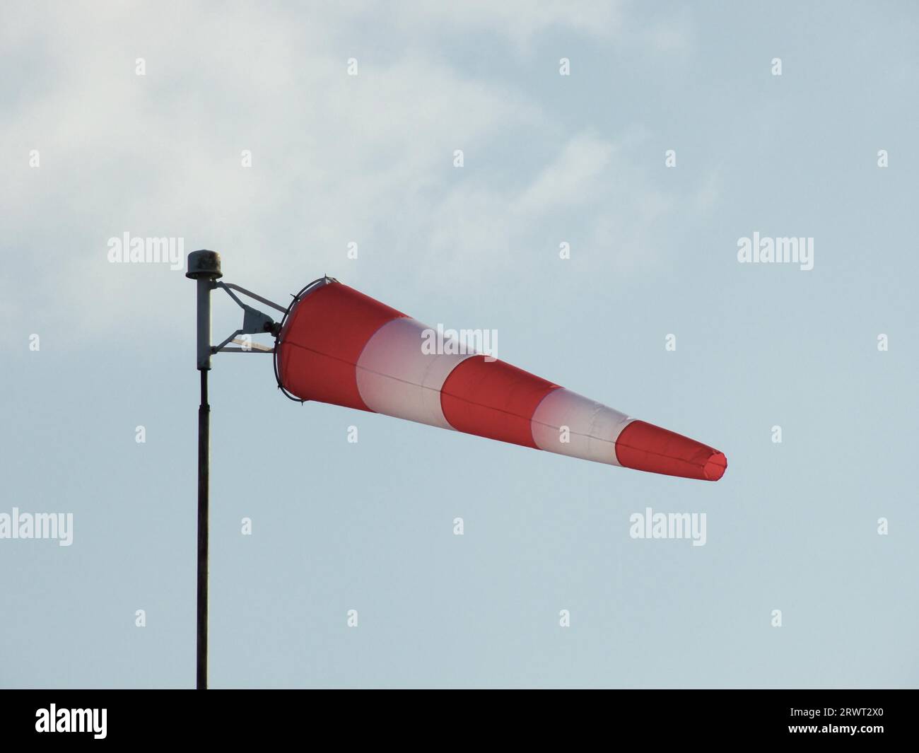 Chaussette gonflée rouge et blanche sur un poteau, ciel gris-bleu en arrière-plan Banque D'Images