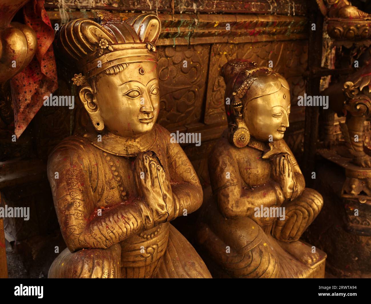 Statues métalliques dorées d'un homme et d'une femme assis et priant, Temple d'or Hiranya Varna Mahavihar, Patan, Népal, Asie Banque D'Images