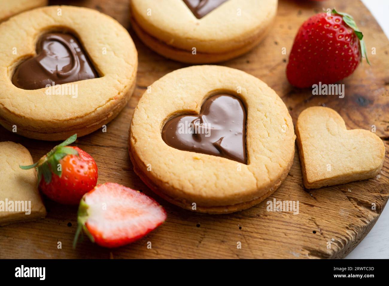 Biscuits au beurre avec des coeurs remplis de crème au chocolat et de fraises. Banque D'Images