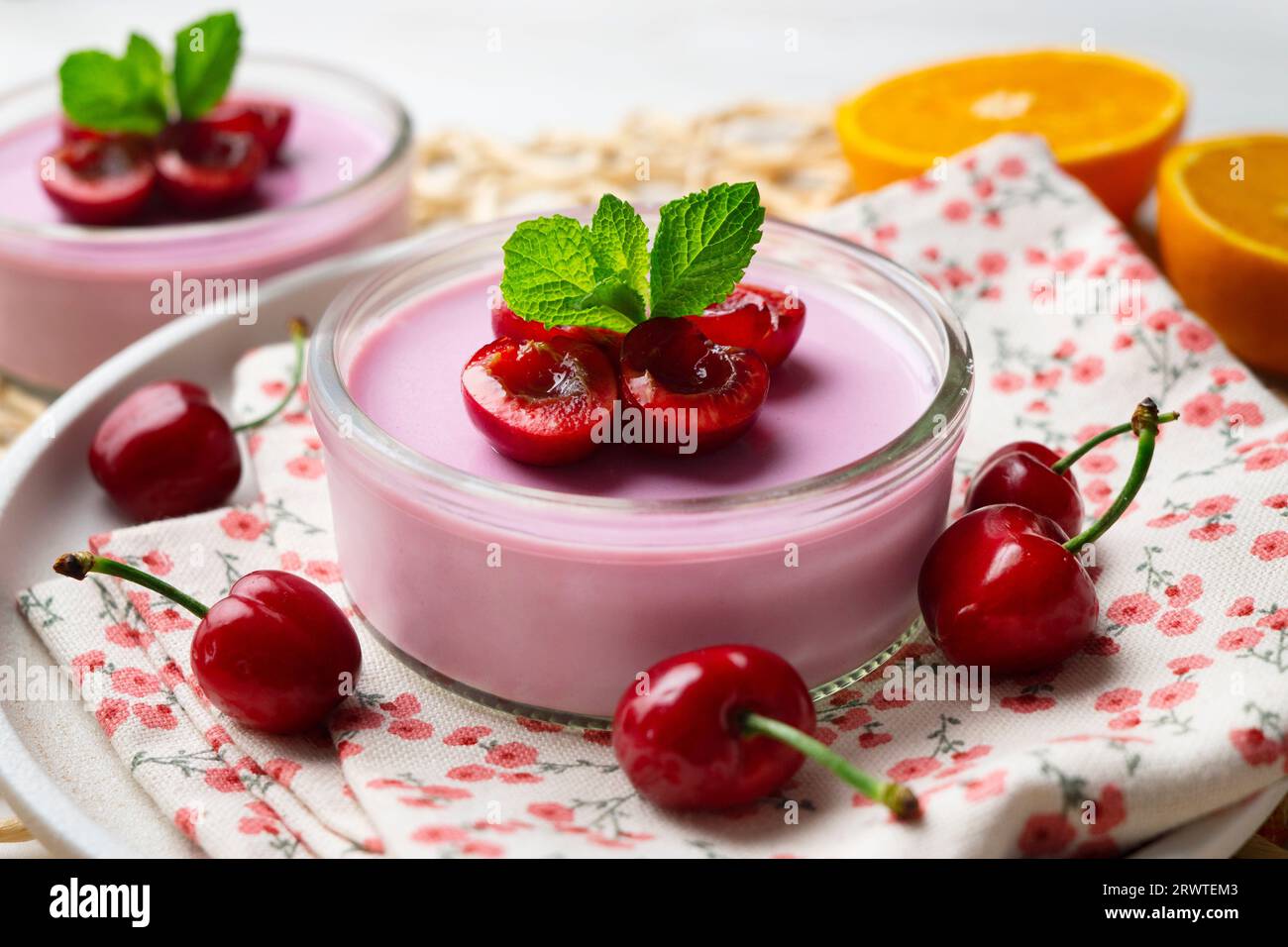 Panna cotta à la cerise servie dans un verre avec des fruits frais et du chocolat râpé. Banque D'Images