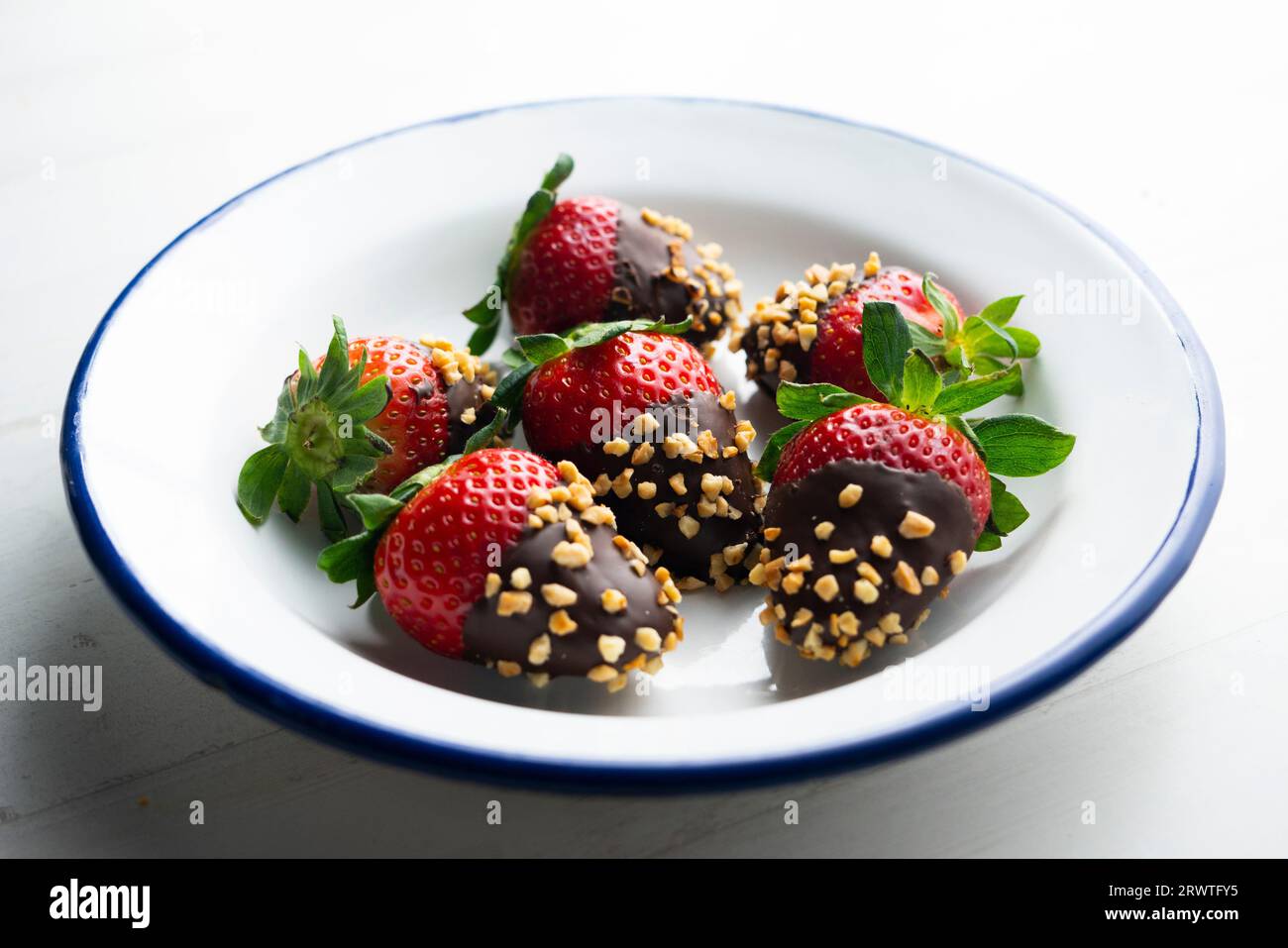 Fraises trempées dans du chocolat noir et enrobées d'amandes grillées. Banque D'Images