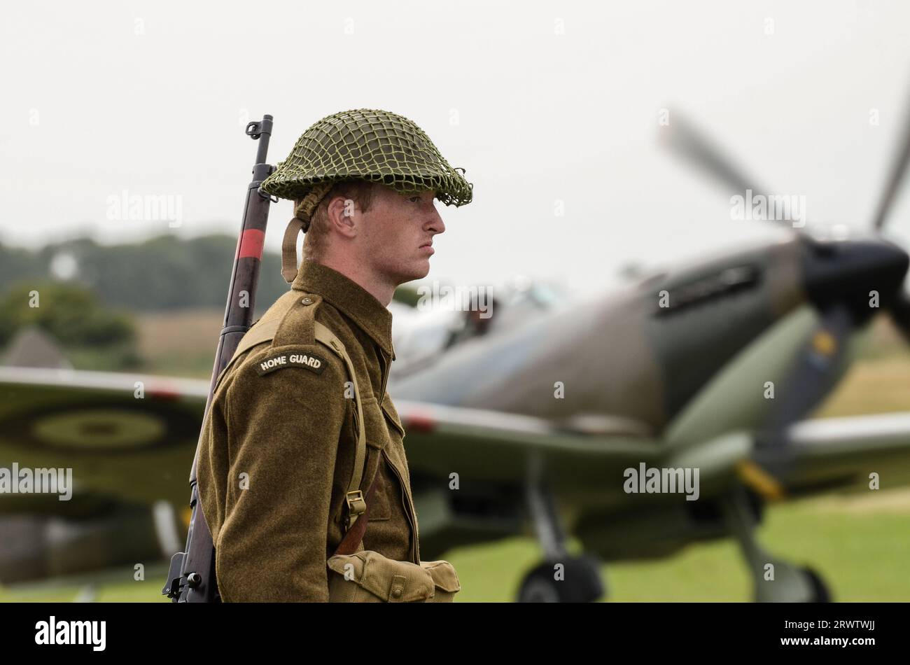 Jeune Home Guard réacteur à un spectacle aérien, avec un avion de chasse Supermarine Spitfire de la Seconde Guerre mondiale. Garde à une reconstitution d'aérodrome Banque D'Images