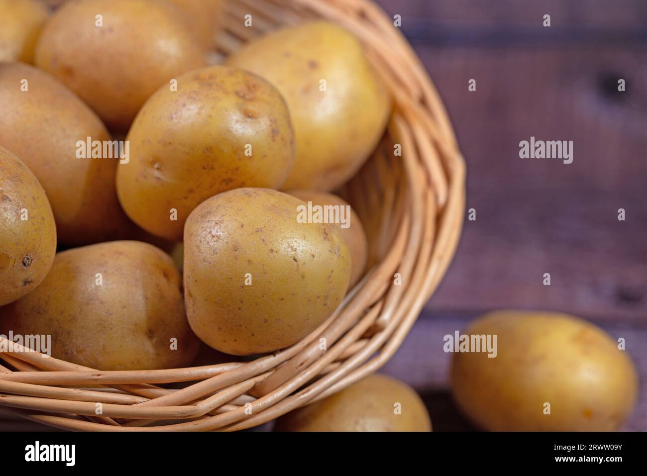 Pommes de terre dans le panier sur fond de bois Banque D'Images