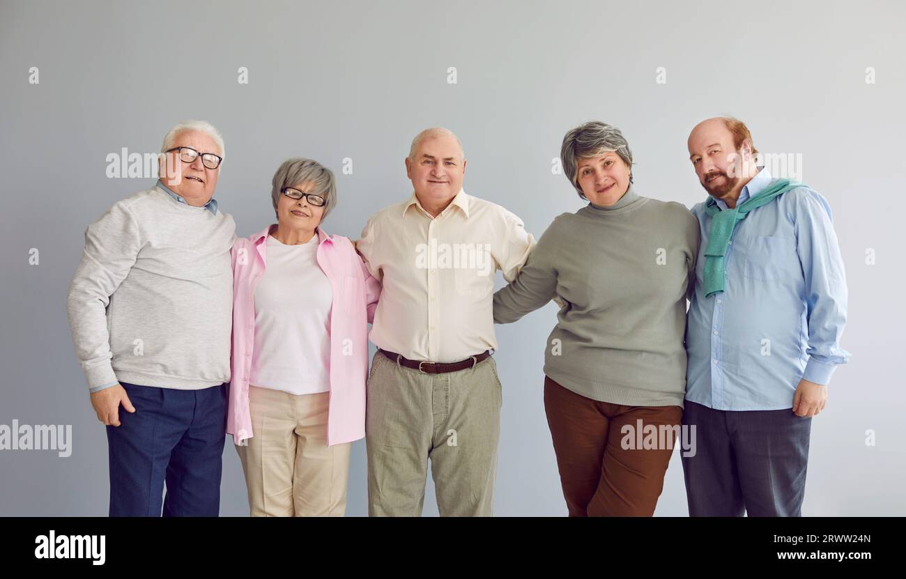 Portrait de groupe d'hommes et de femmes retraités âgés heureux debout ensemble et étreints Banque D'Images