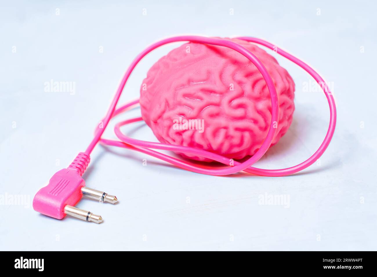 Modèle anatomique d'un cerveau humain ayant un cordon d'alimentation de couleur correspondante isolé sur un fond concret. Concept lié à la recharge cérébrale. Banque D'Images