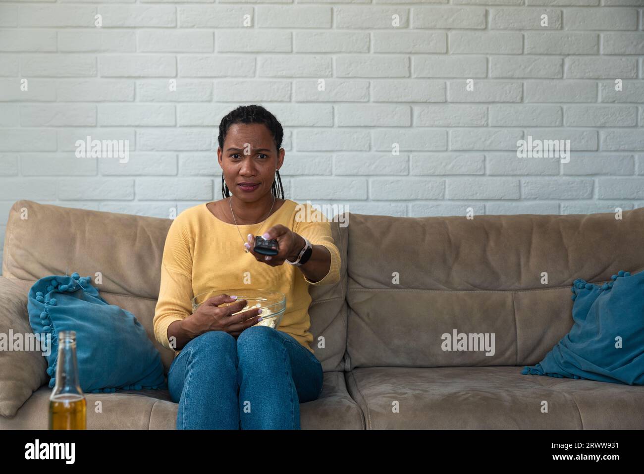 Jeune femme effrayée assise seule à la maison sur le canapé regardant un film d'horreur effrayant à la télévision. Dégoûté amoureux des animaux femelle a vu la cruauté des animaux t Banque D'Images