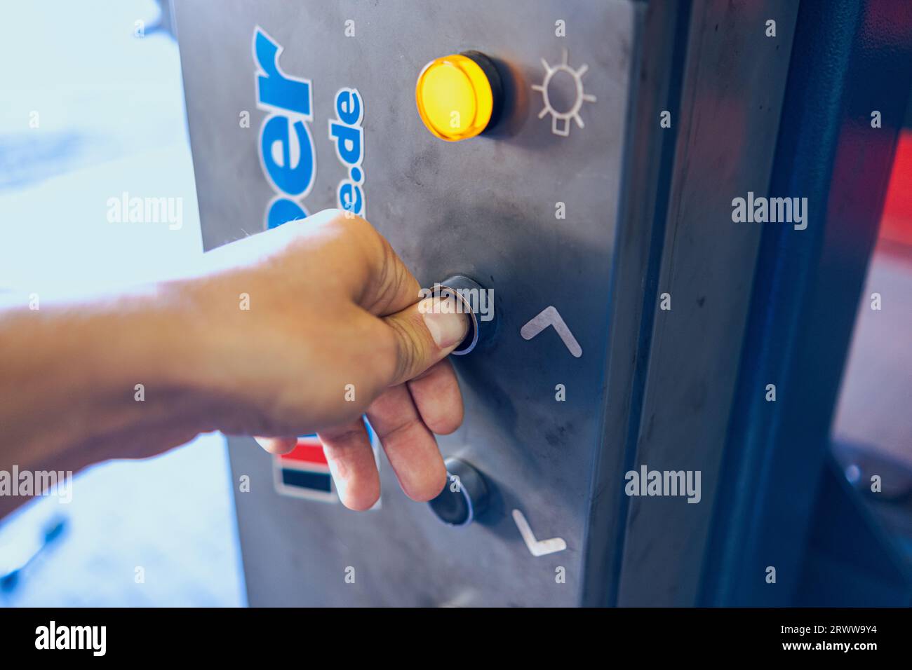 Le doigt appuie sur le bouton de l'ascenseur de voiture. Soulever le panneau de commande. Le voyant jaune est allumé. Banque D'Images