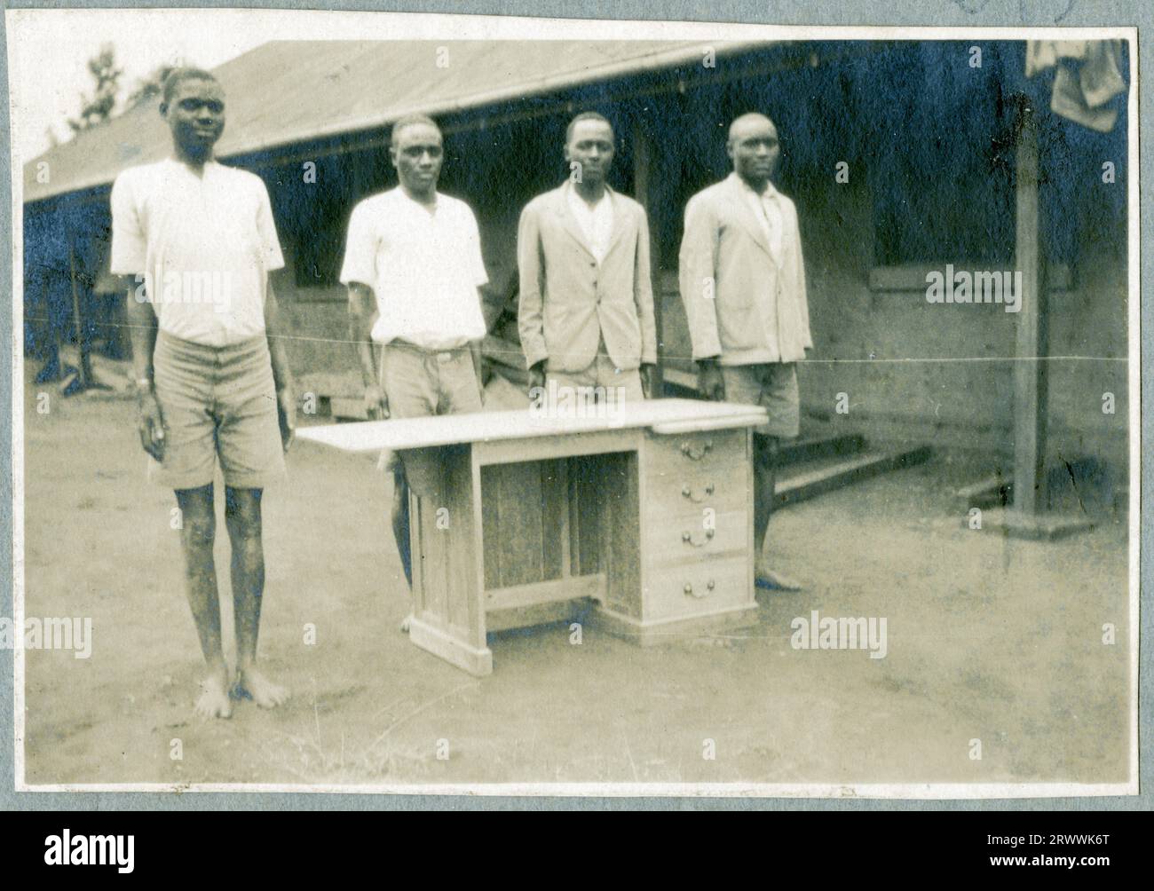 Quatre apprentis posent en dehors de leur atelier avec leur bureau terminé. Probablement à l'école autochtone d'Ukamba. Banque D'Images