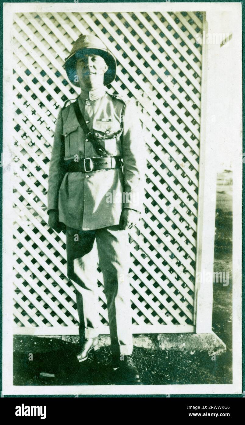 Portrait d'un homme européen en uniforme de style militaire et d'un casque de moelle avec badge de police, debout devant un écran. Légende originale du manuscrit : E.P.C. Thomas, 'E.A. police'. Banque D'Images