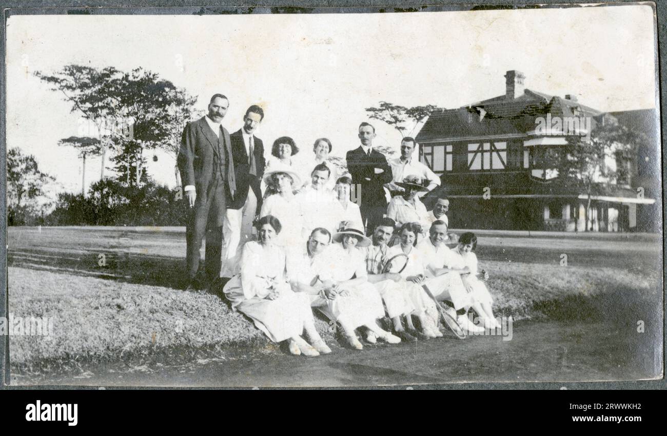 Un grand groupe d'hommes et de femmes européens, la plupart vêtus de blancs de tennis et certains tenant des raquettes, posent pour une photo dans le parc de Government House, Nairobi. Le bâtiment lui-même est visible à leur droite. Légende originale du manuscrit : tennis Party Govt. Maison. Banque D'Images