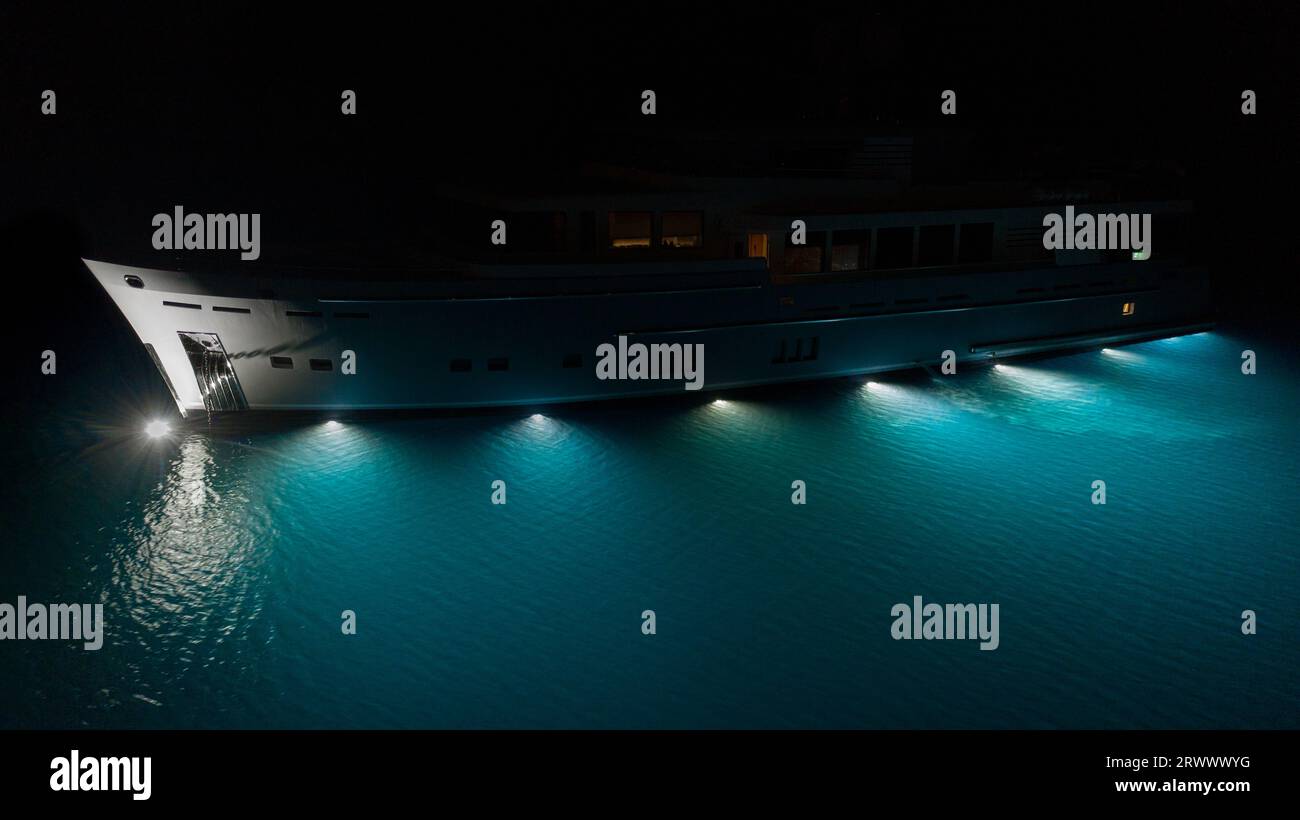Yacht à moteur de luxe, superbes lumières sous-marines illuminant les eaux turquoise bleues de Cavtat Bay, Croatie. Éclairage sous bateau Banque D'Images