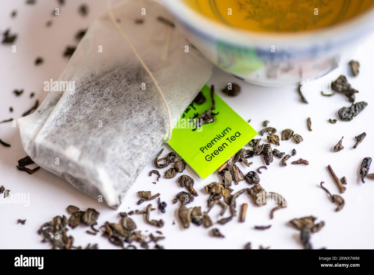 Feuilles de thé vert en vrac et sachets de thé avec une tasse de thé vert isolé en blanc. Boisson santé, concept de mode de vie sain. Banque D'Images