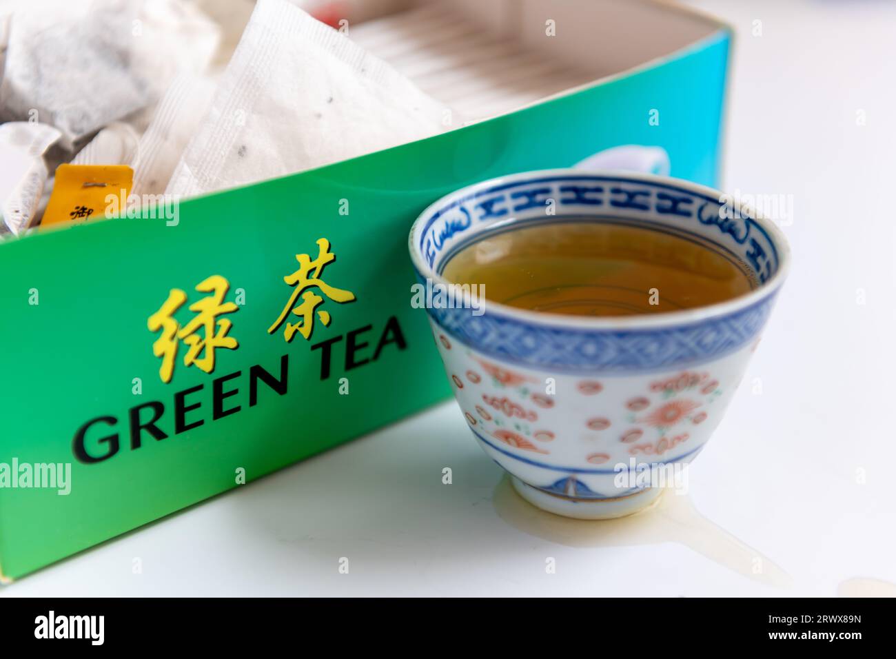 Une tasse de thé vert par une boîte de sachets de thé isolés en blanc. Boisson saine, concept de style de vie. Banque D'Images