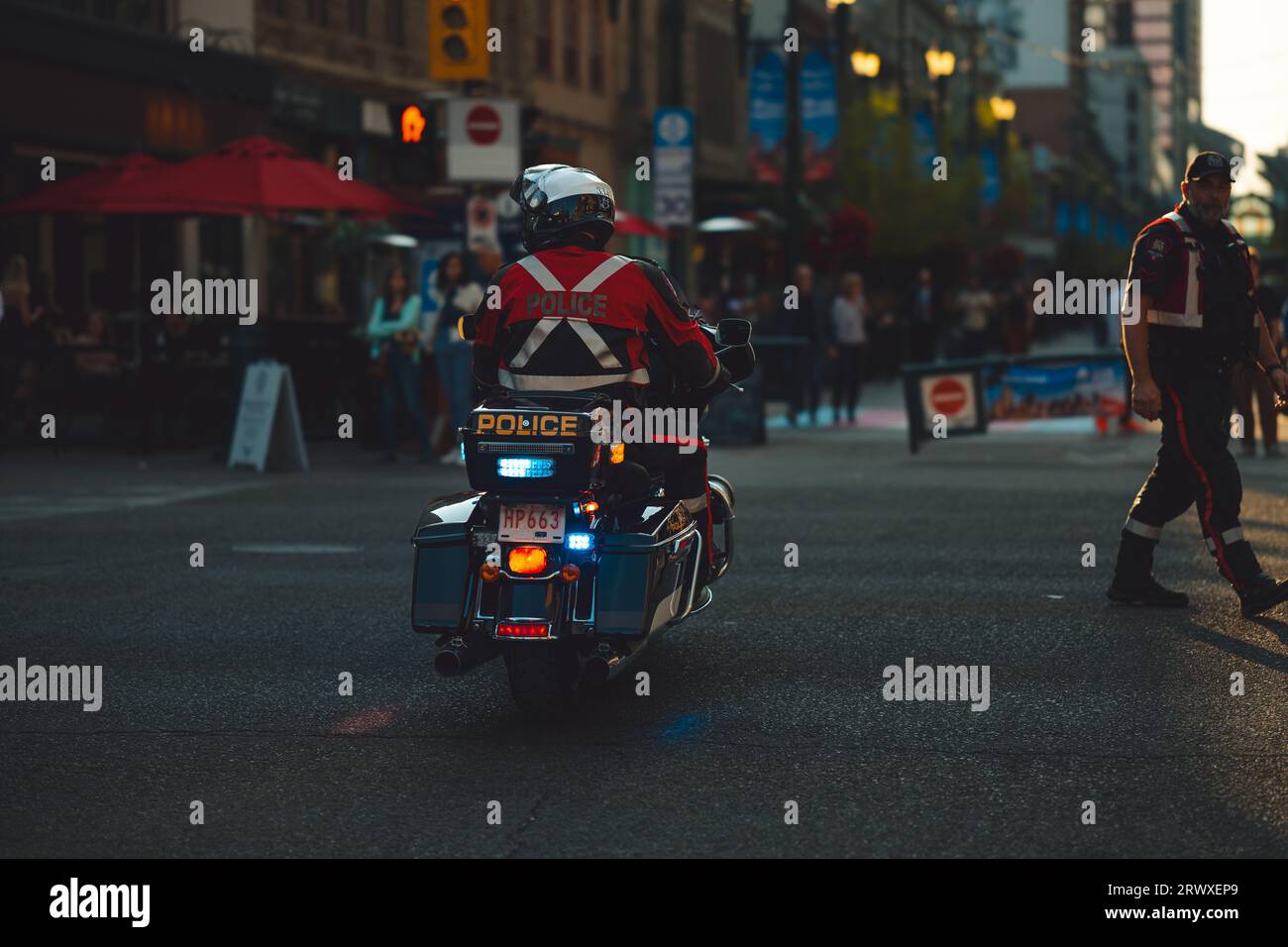 Un policier à moto traverse la chaussée avec ses feux de secours activés. Banque D'Images