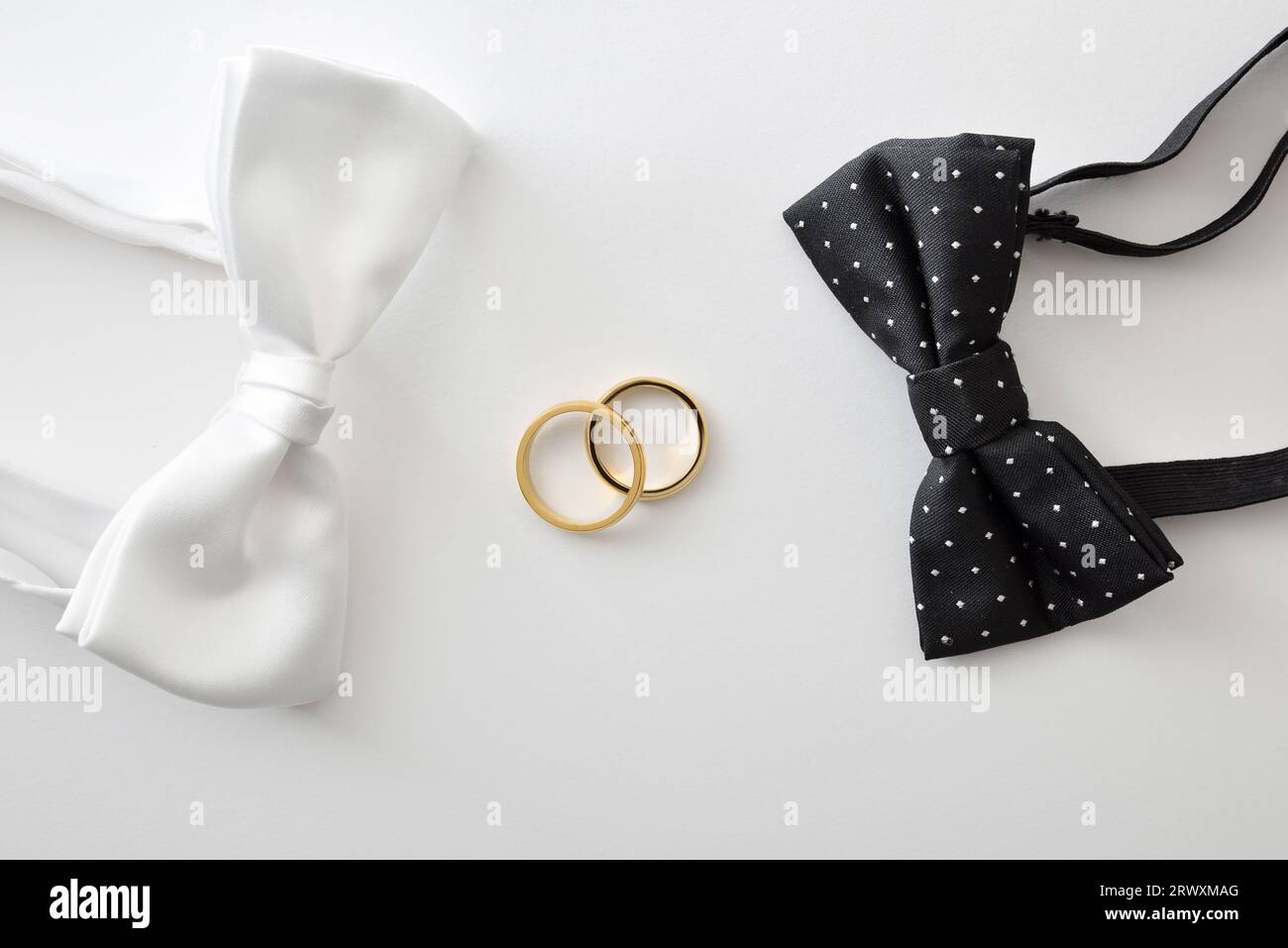 Concept de mariage gay avec noeud papillon noir avec pois et blanc sur les côtés des anneaux de mariage au centre. Vue de dessus. Banque D'Images