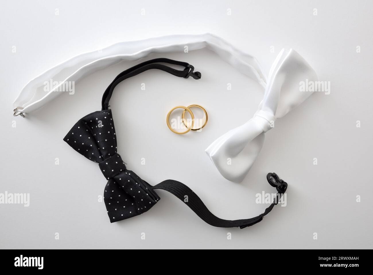 Fond de mariage gay conceptuel avec noeud papillon noir et blanc entourant les anneaux de mariage. Vue de dessus. Banque D'Images
