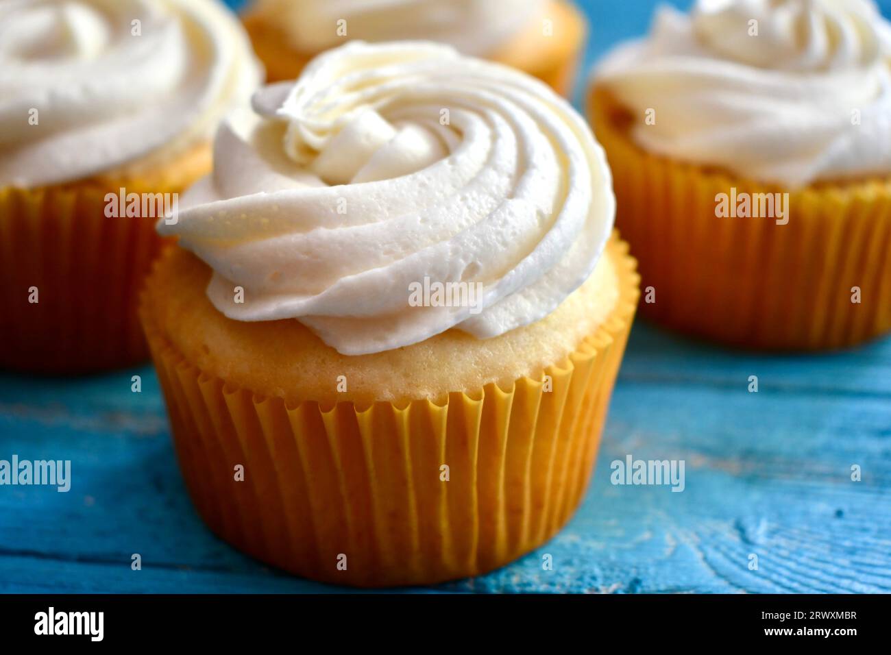 Cupcake vanille dans une tasse de papier jaune sur un fond de bois bleu Banque D'Images