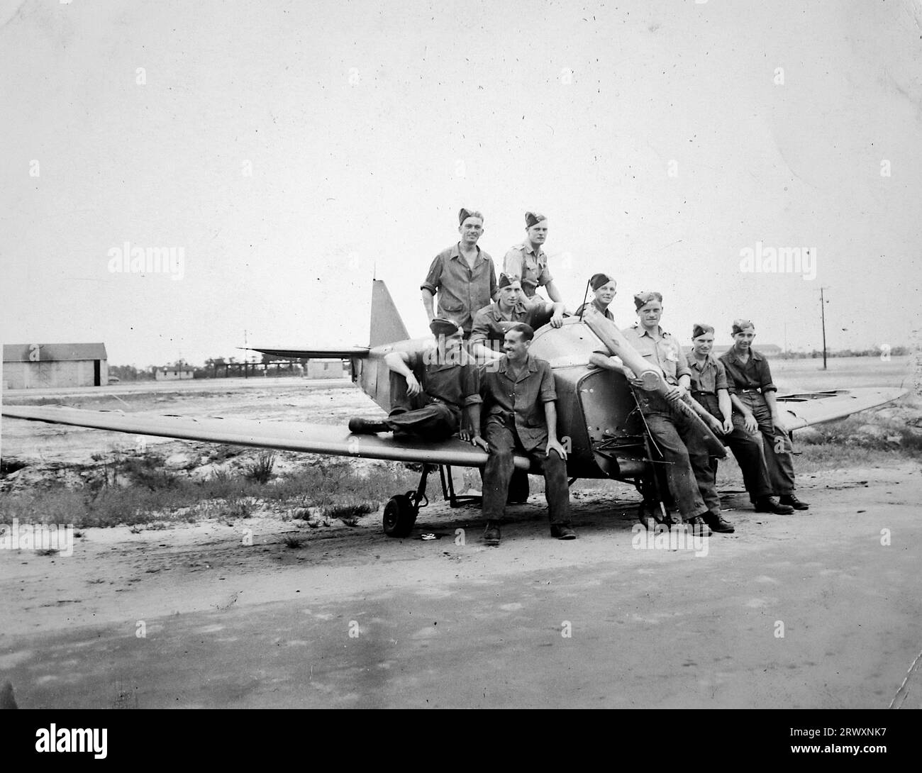 Une photographie de groupe montrant du personnel détendu sur et autour d'un petit avion. Rare photographie provenant d'une collection compilée par un militaire britannique inconnu couvrant la démonstration composite n°1, batterie AA, tournée des Etats-Unis, du 11 juillet 1943. Il s'agit d'une parmi plus d'une centaine d'images de la collection qui étaient en moyenne autour de 4x3 pouces. Banque D'Images