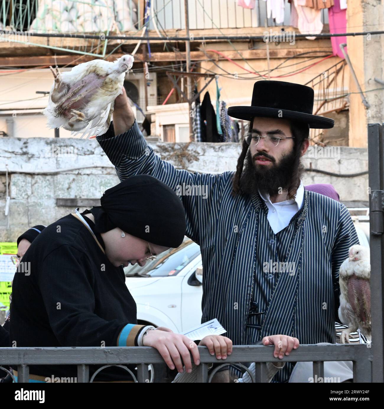Jérusalem, Israël. 21 septembre 2023. Un juif ultra-orthodoxe balance un poulet sur la tête d'une femme lors de l'ancien rituel Kapparot à Mea Shearim à Jérusalem, le jeudi 21 septembre 2023. Kapparot est préformé avant Yom Kippour, le jour des Expiations, le jour le plus sacré du calendrier juif, et transfère symboliquement les péchés de l'année passée au poulet. Photo de Debbie Hill/ crédit : UPI/Alamy Live News Banque D'Images