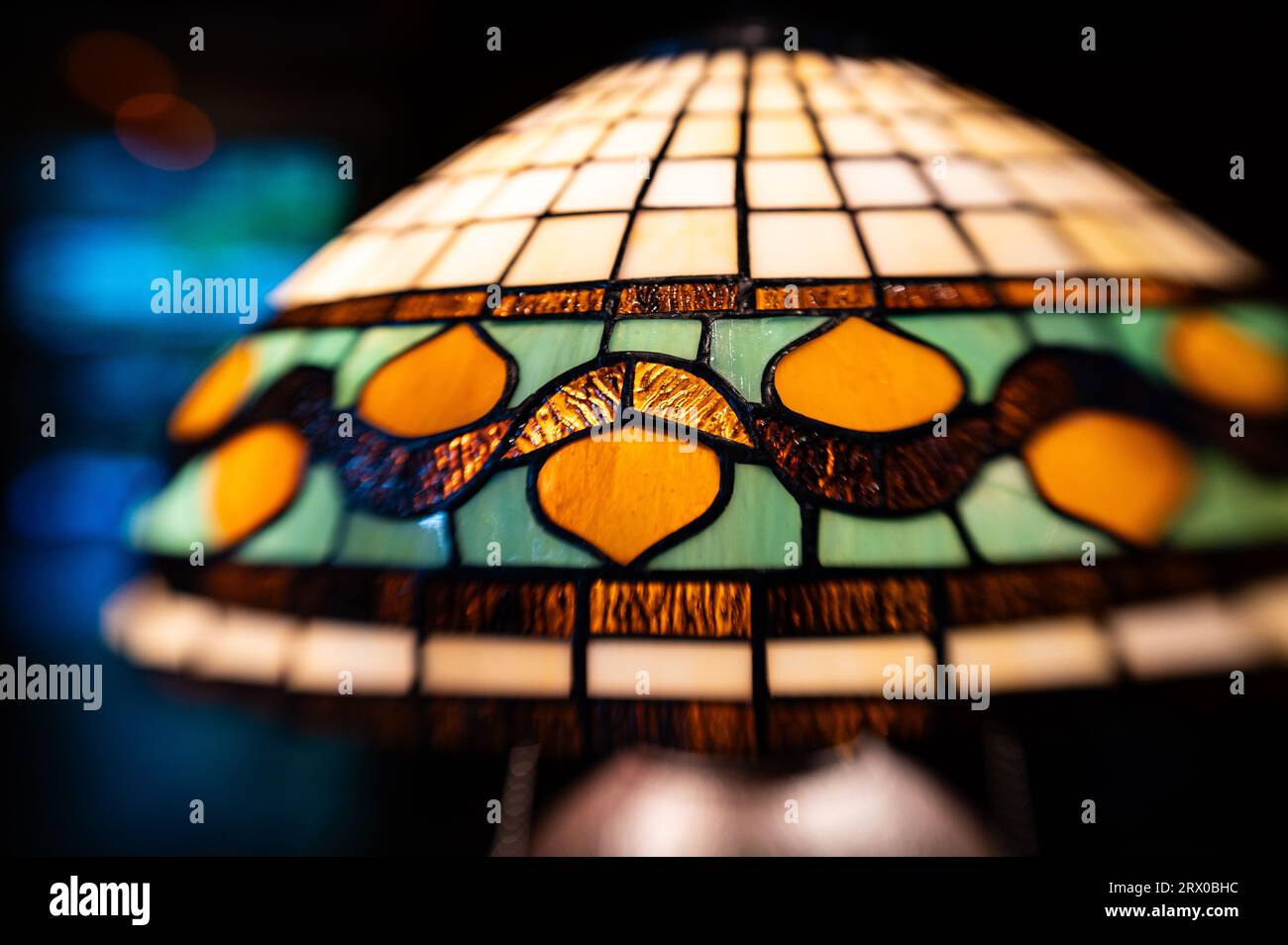 Image de mise au point sélective prise avec une lentille Lensbaby d'une lampe en verre de style art déco colorée avec motif orange abstrait et carreaux. Banque D'Images