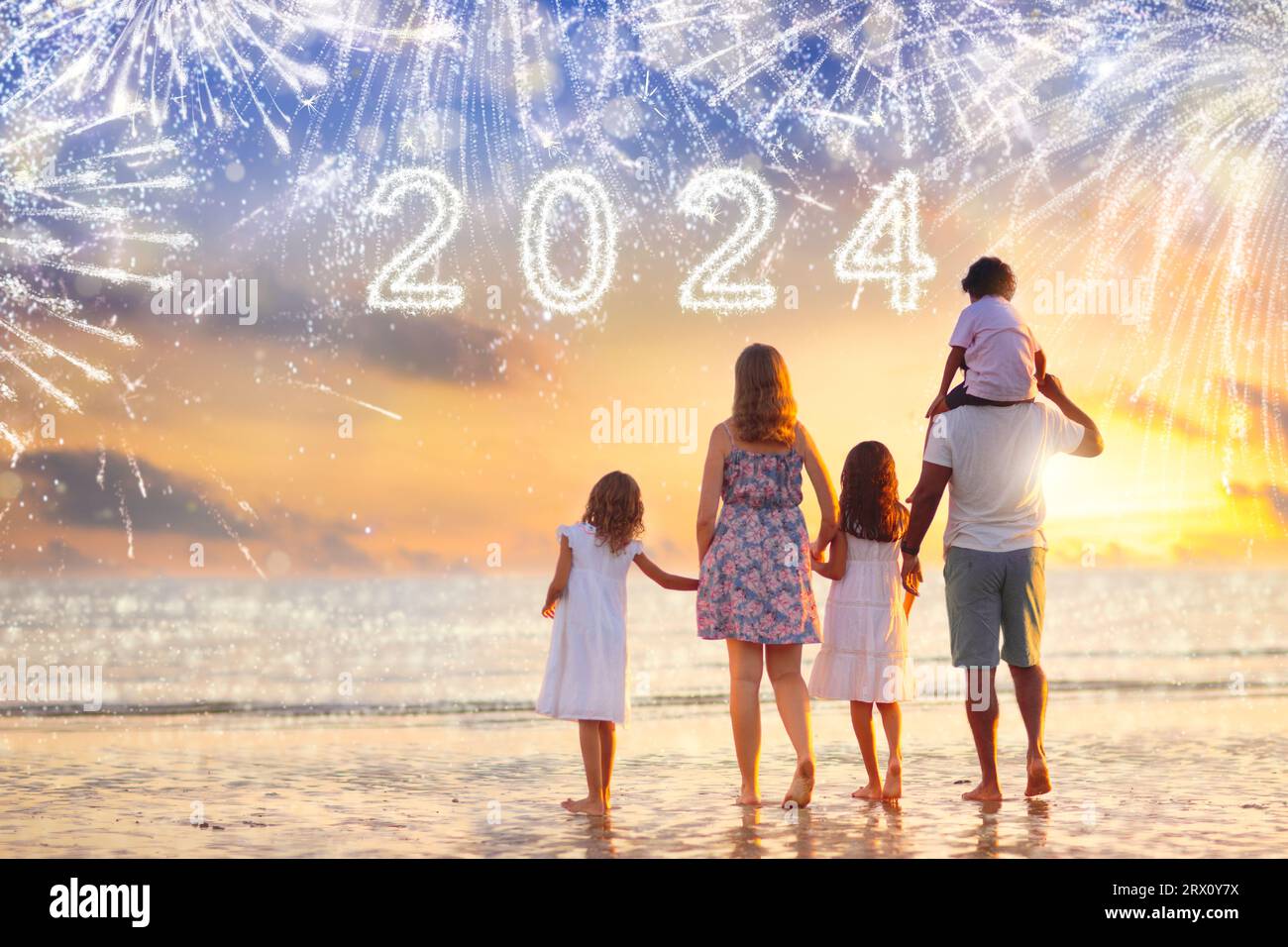 Bonne année. Foule regardant les feux d'artifice sur la plage tropicale. Les parents et les enfants célèbrent la nouvelle année 2024. Fête de vacances dans une destination exotique. Banque D'Images
