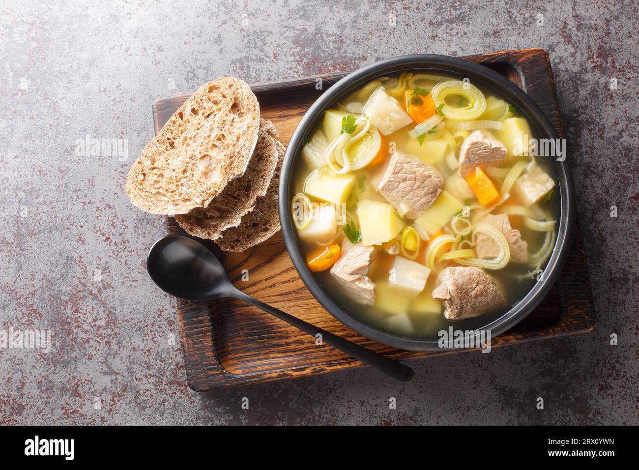 Soupe Kottsoppa avec viande bouillie, carottes hachées, oignons, panais, céleri et poireaux gros plan sur une assiette sur la table. Vue de dessus horizontale Banque D'Images