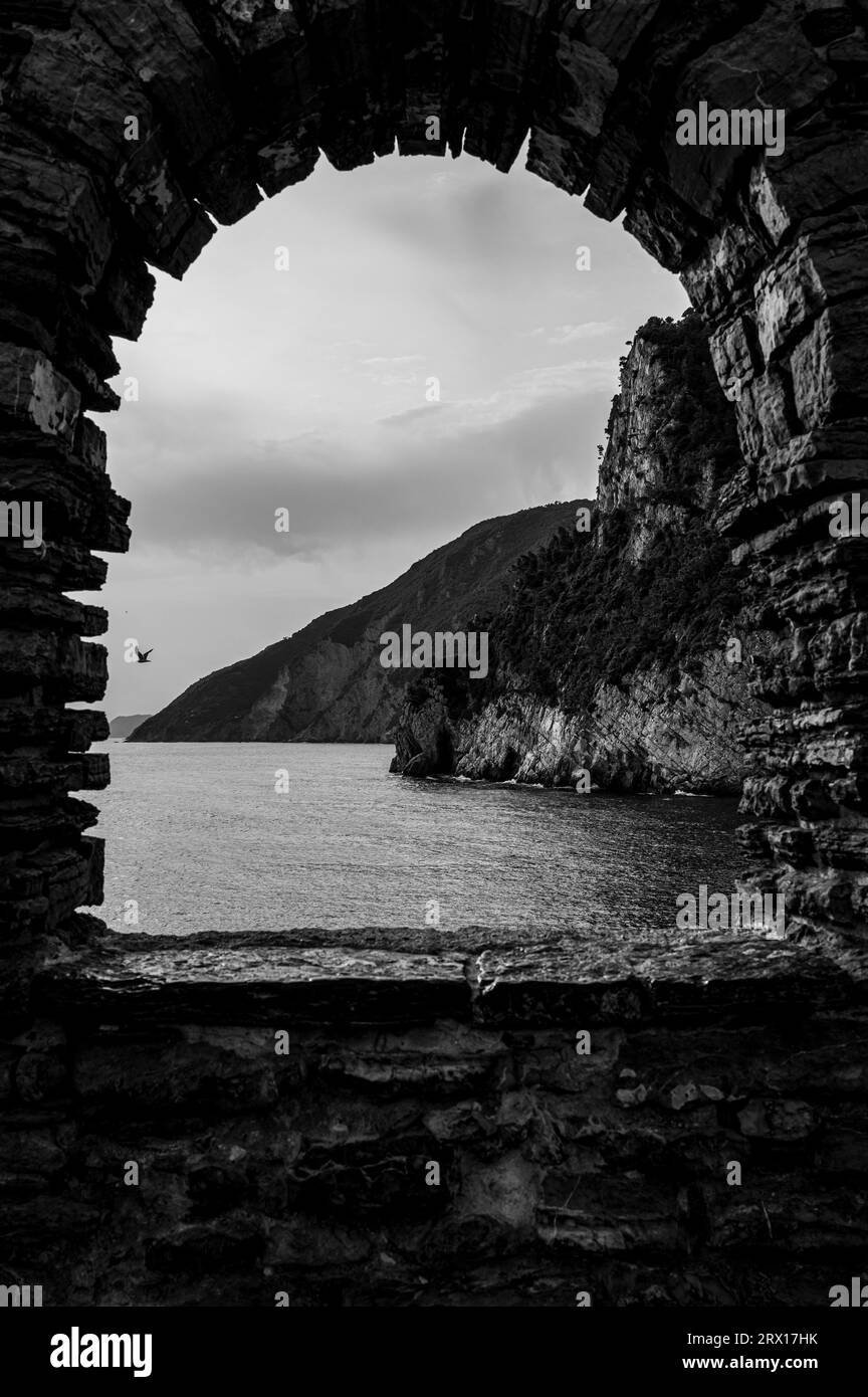 Une arche en pierre menant à une vue imprenable sur la mer et les montagnes au-delà en Italie. Banque D'Images