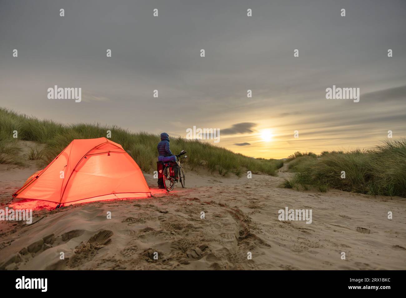 Homme avec Touring Bicycle Camping sur la plage sous la pleine lune Banque D'Images