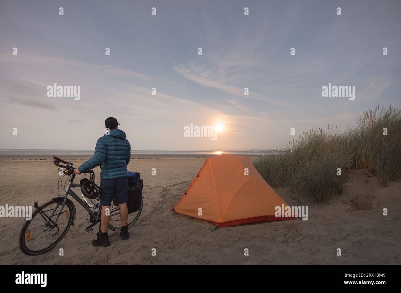 homme avec vélo de randonnée camping sur la plage sous la pleine lune Banque D'Images