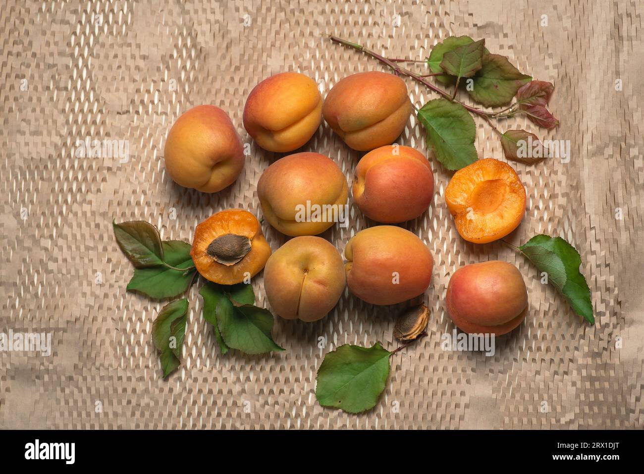 Abricots frais, mûrs et juteux sur un fond clair. Fruits entiers, avec feuilles, moitiés d'abricot Banque D'Images