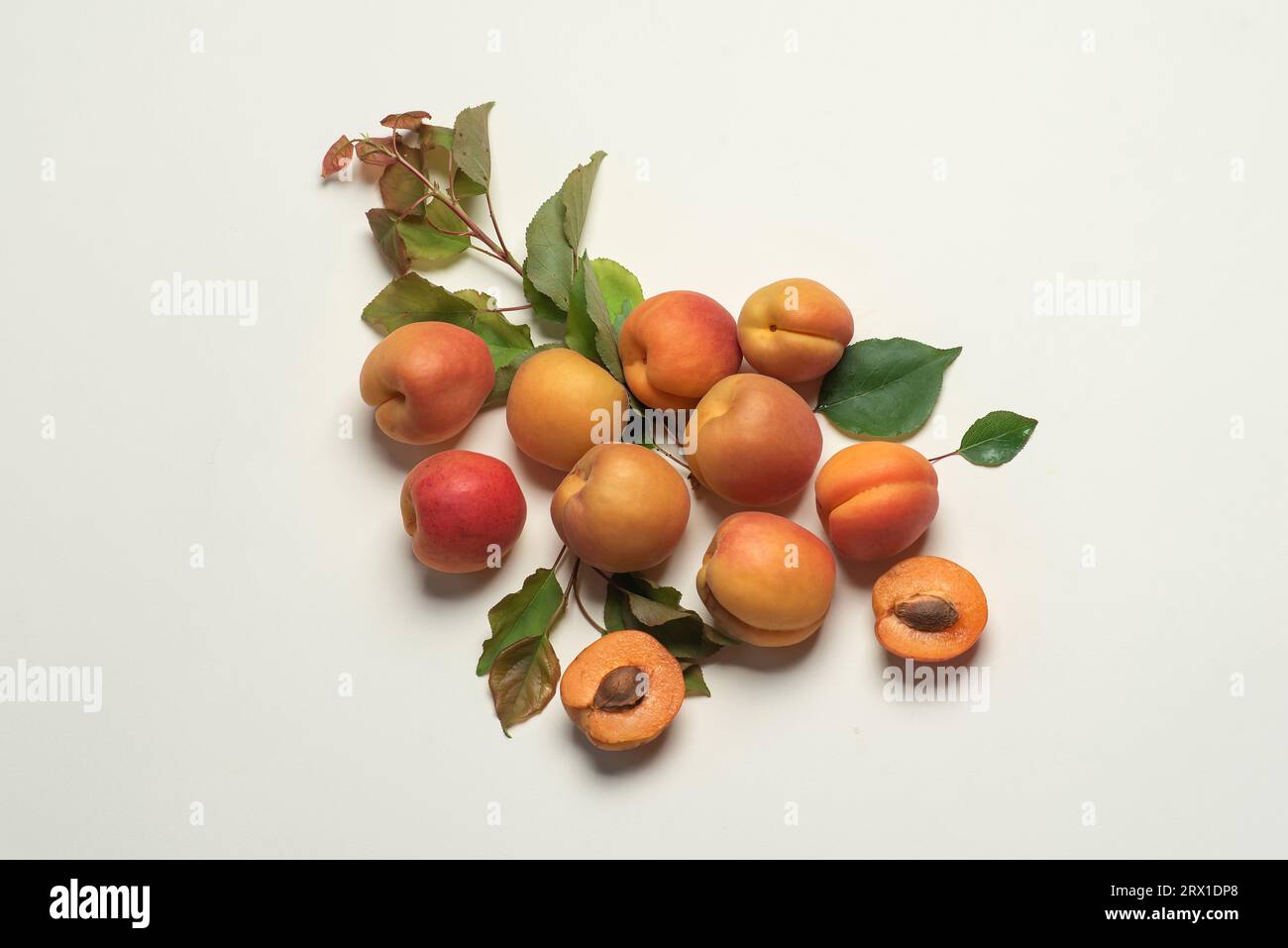 Abricots frais, mûrs et juteux sur fond blanc. Fruits entiers, avec feuilles, moitiés d'abricot Banque D'Images