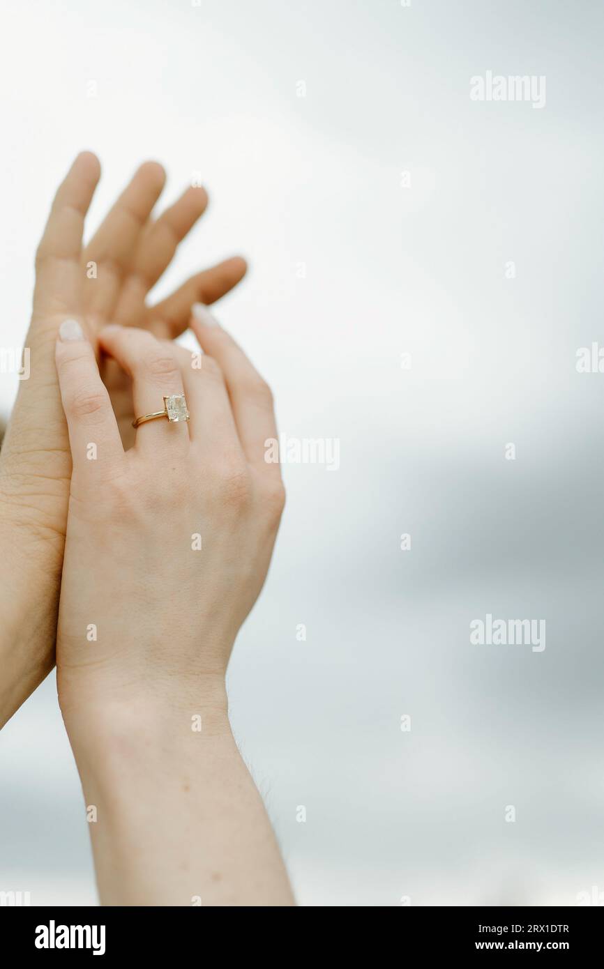 Mains levées vers le ciel, présentant une grande bague en diamant. Banque D'Images