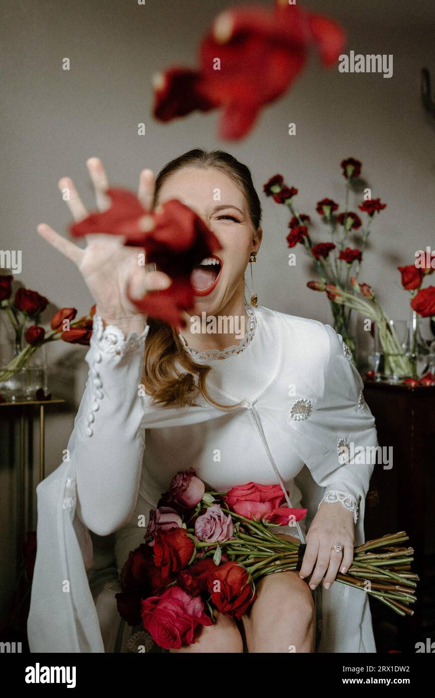Mariée en tenue vintage jette des pétales de rose à la caméra. Banque D'Images