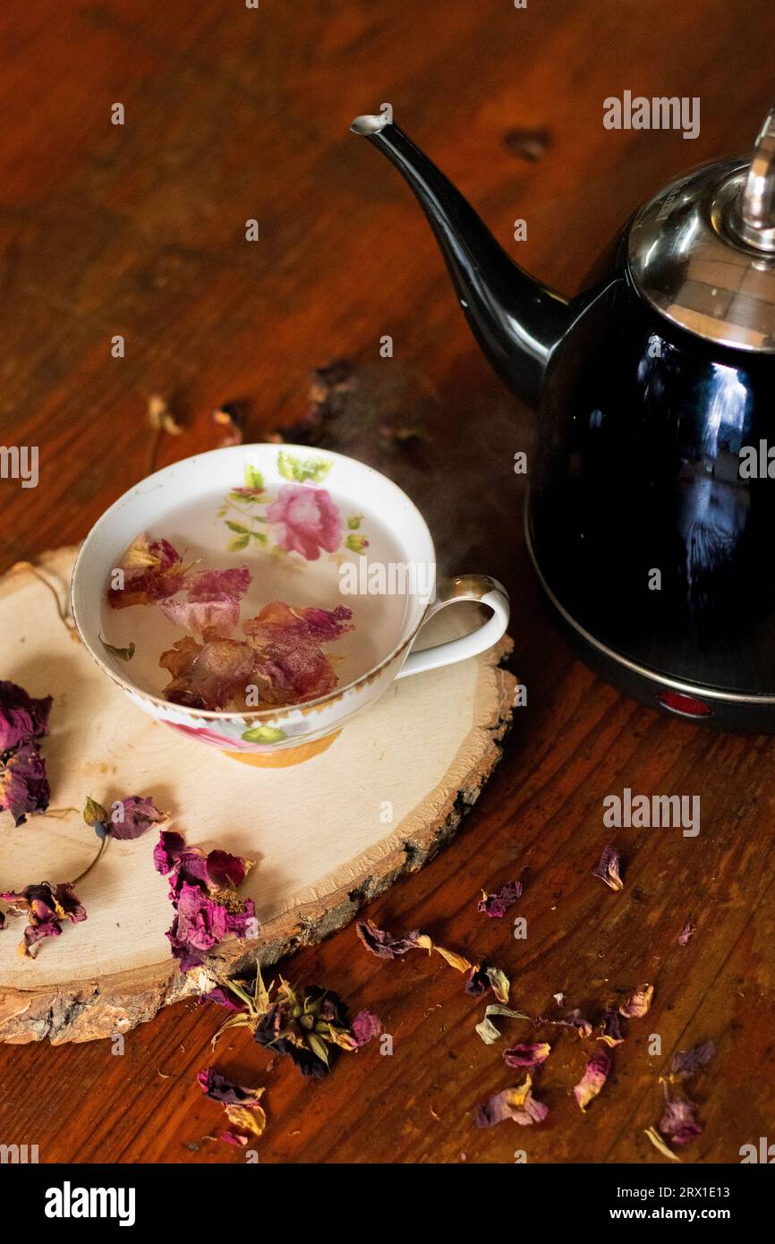 Tasse à thé vintage et théière ; feuilles de rose lâches élégamment dispersées. Banque D'Images