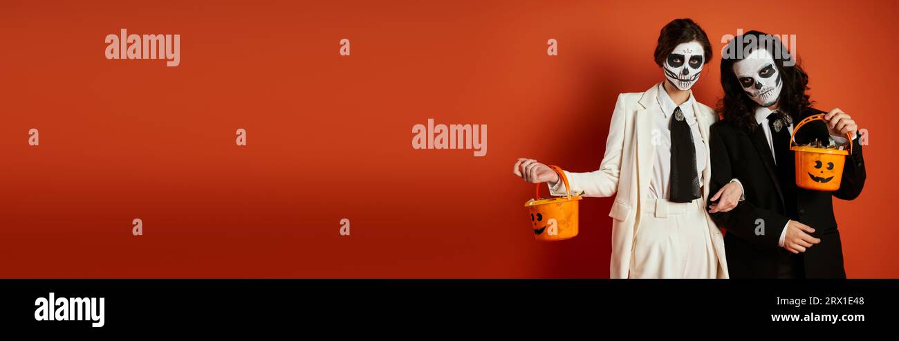 couple élégant en dia de los muertos maquillage et costumes debout avec seaux à bonbons sur rouge, bannière Banque D'Images