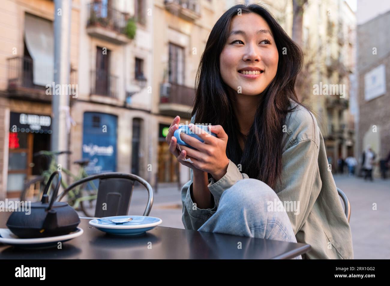 Jeune femme détendue prenant une tasse de thé dans une terrasse de bar. Banque D'Images