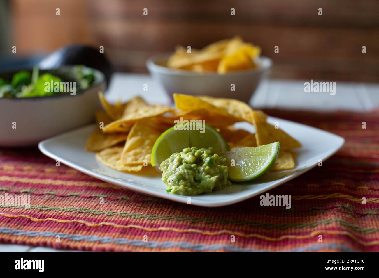 Gros plan de chips, guacamole et citron vert sur plaque blanche Banque D'Images