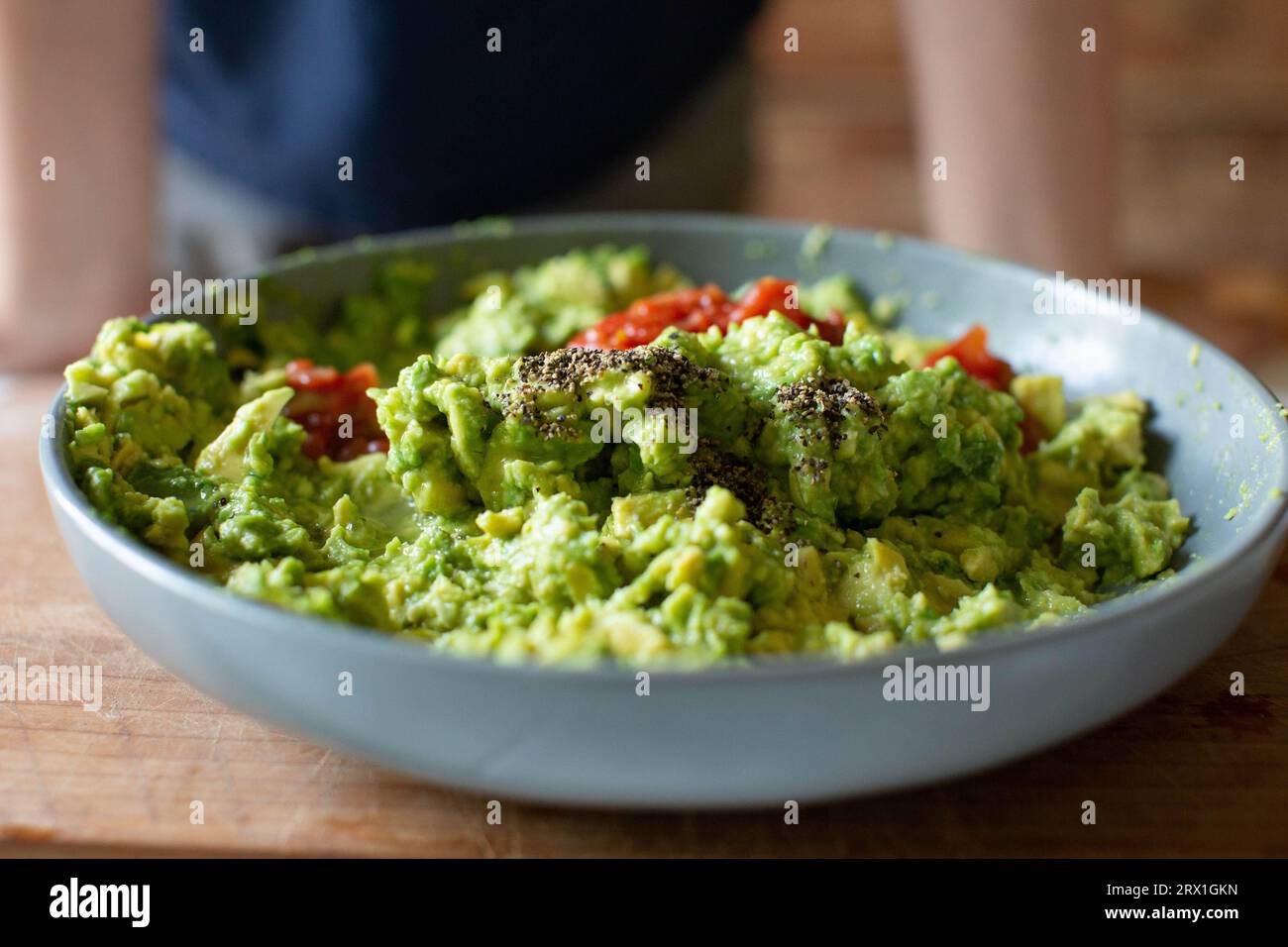 Guacamole fraîchement préparé avec des tomates et du poivre dans un bol gris avec Banque D'Images