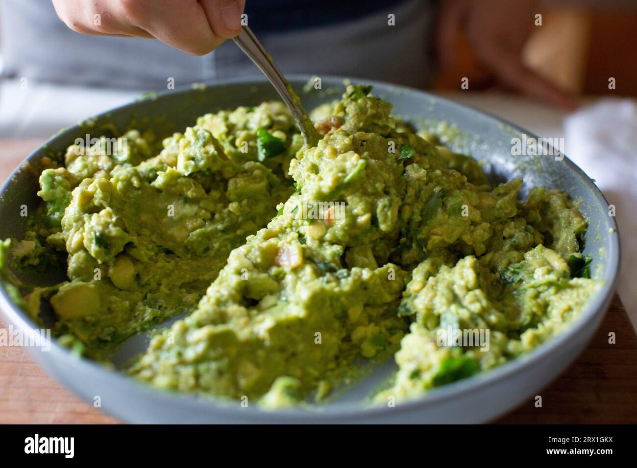 Garçon mélangeant Guacamole frais dans un bol gris Banque D'Images