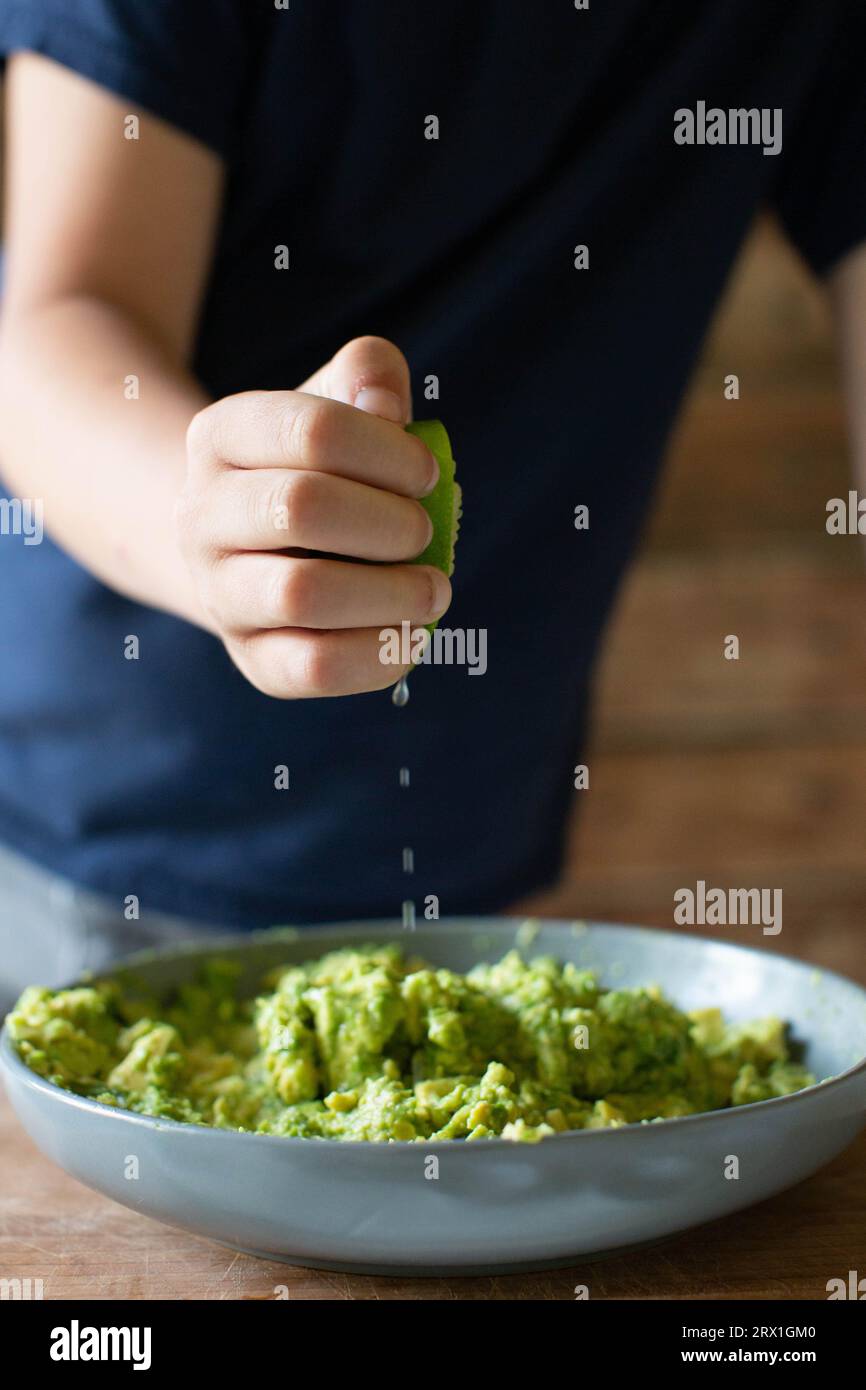 Garçon en chemise bleue serrant Lime dans Guacamole Banque D'Images