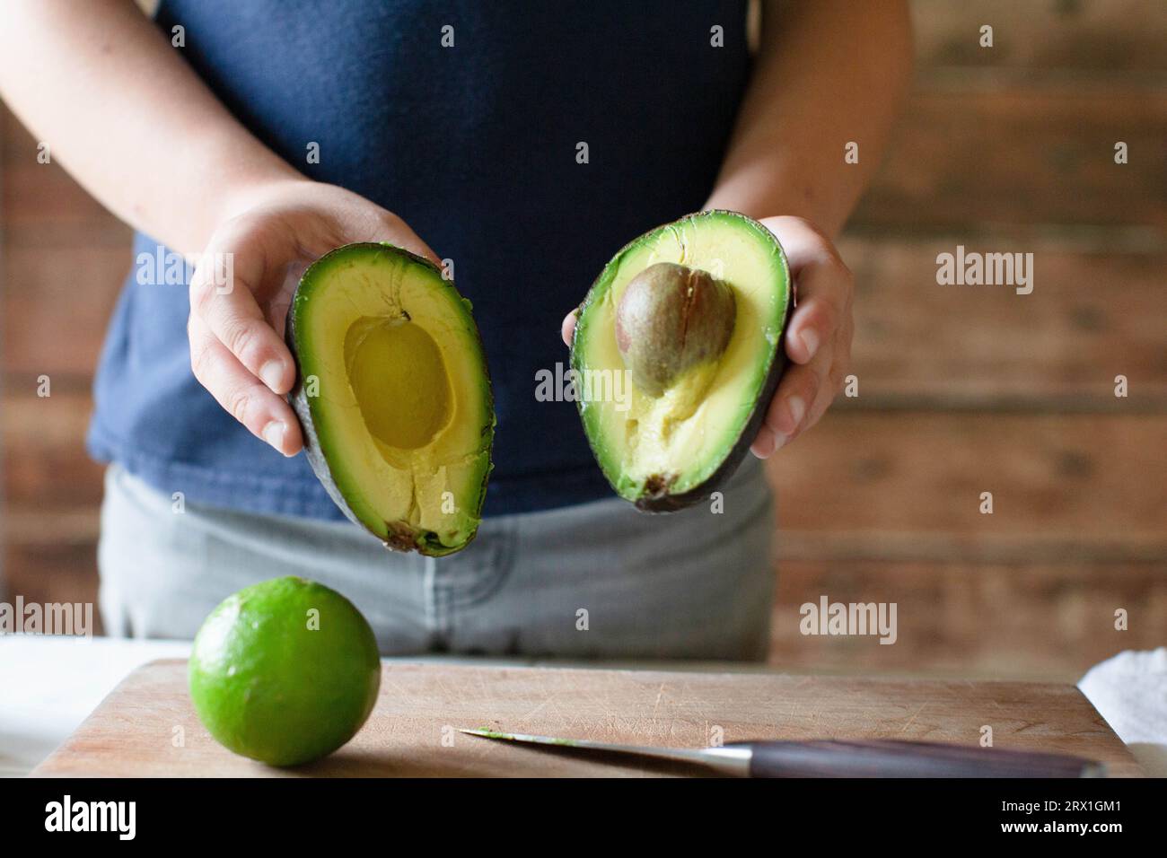 Garçon en chemise bleue tenant avacado tranché en deux Banque D'Images