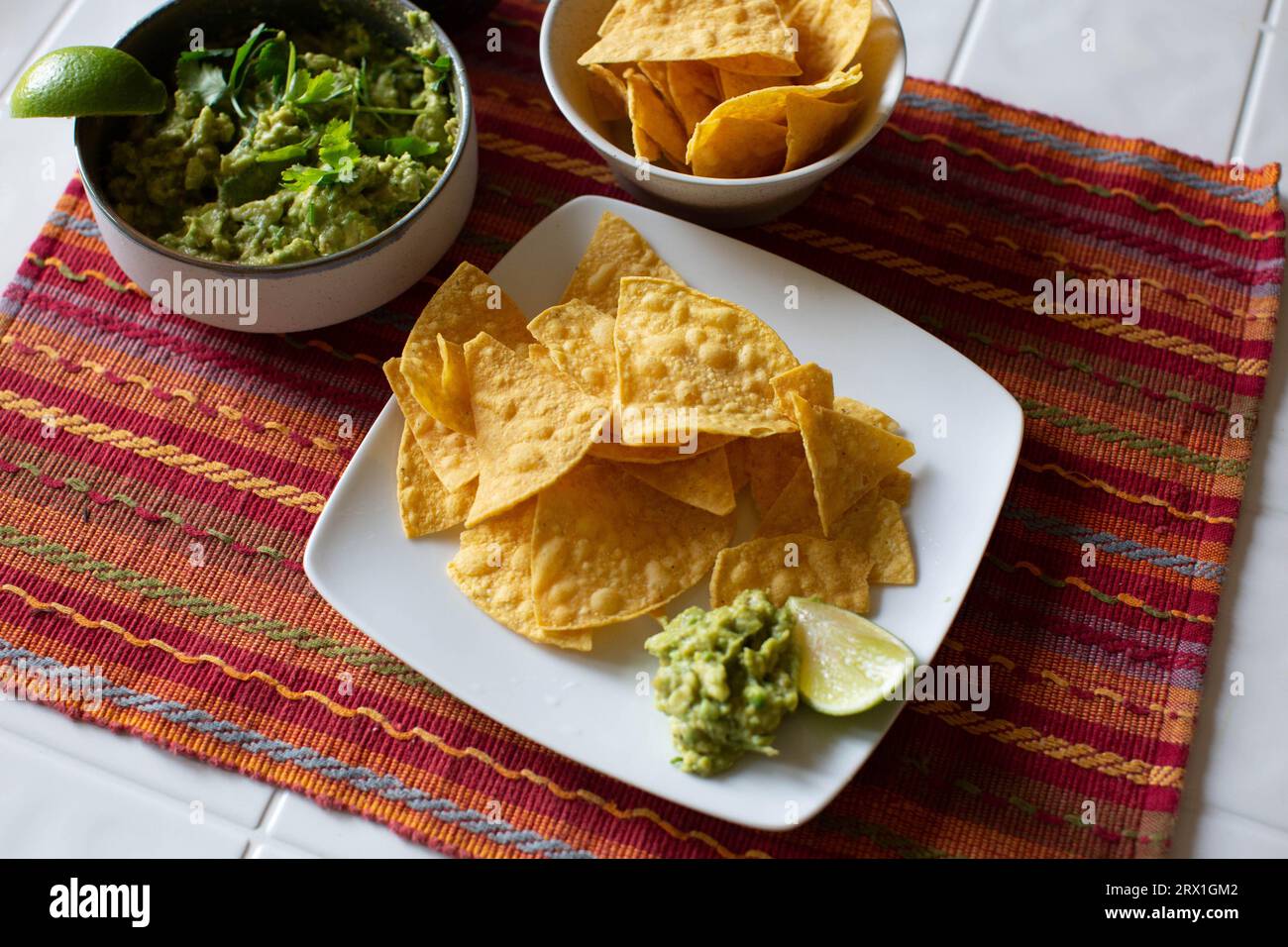 Chips et guacamole sur plaque blanche avec napperon lumineux Banque D'Images