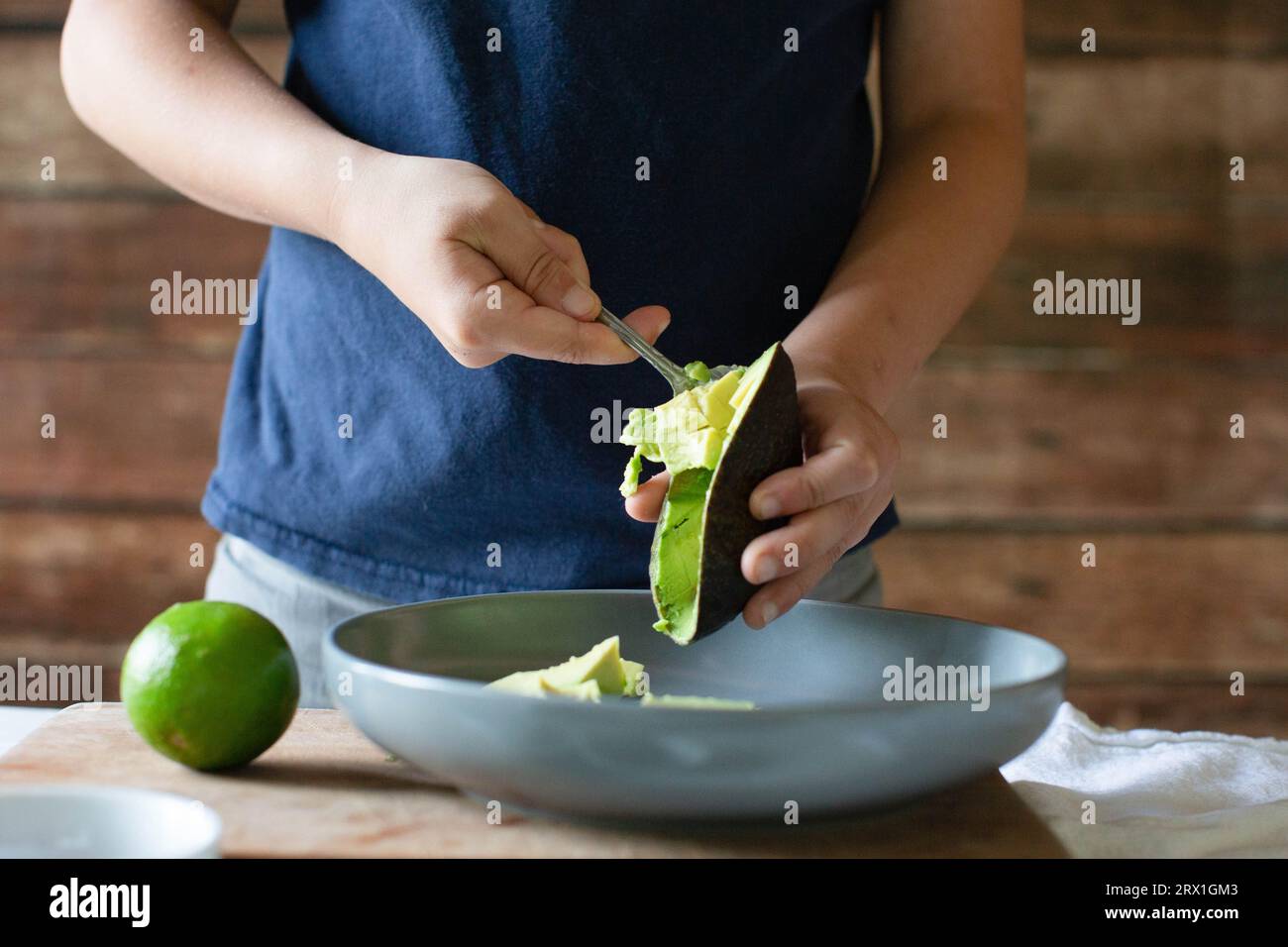 Garçon en chemise bleue scooping avacado dans un bol gris Banque D'Images