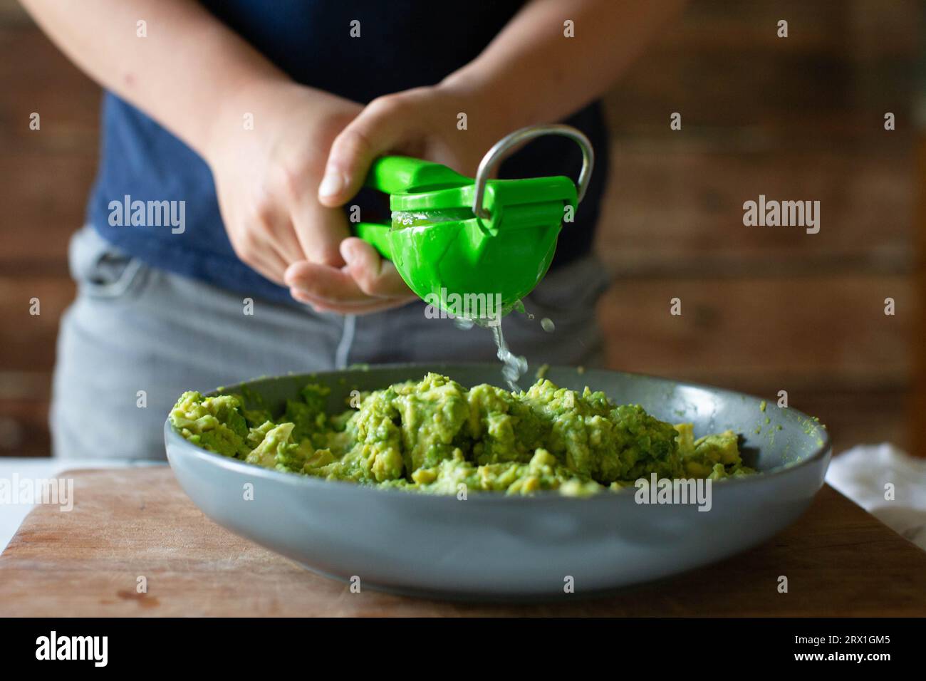 Garçon utilisant Citrus Press pour presser la chaux dans Guacamole Banque D'Images