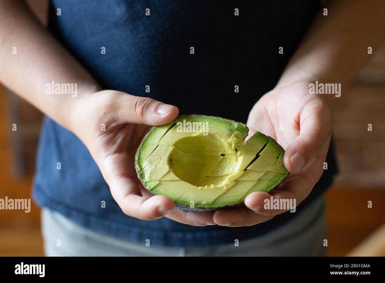 Garçon en chemise bleue tenant Sliced Avacado Banque D'Images